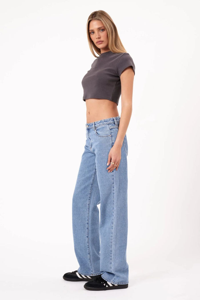 Woman wearing a gray crop top and blue jeans on a white background