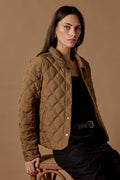 Woman wearing a quilted brown jacket against a brown background