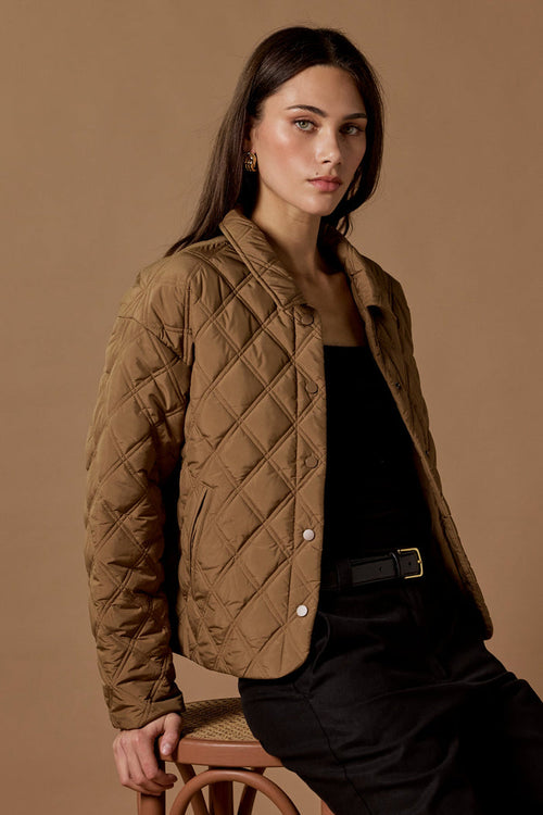 Woman wearing a quilted brown jacket against a brown background
