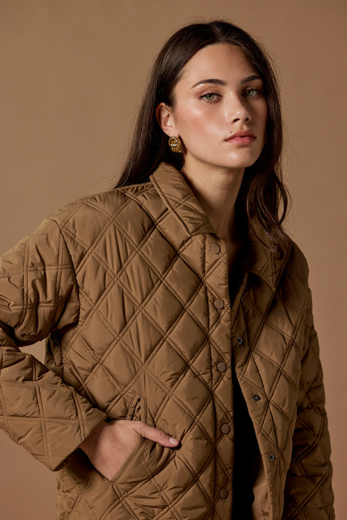 Woman wearing a quilted brown jacket against a beige background