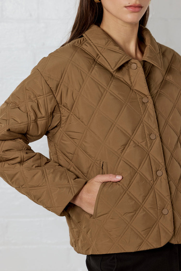 Brown quilted jacket worn by a person on a plain background