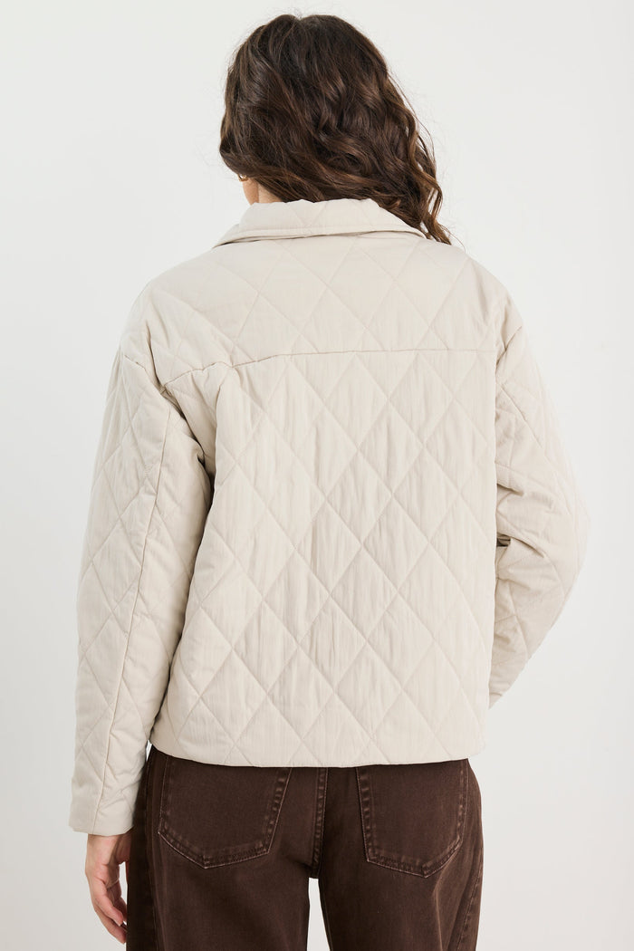 Person wearing a beige quilted jacket on a white background
col_pattern