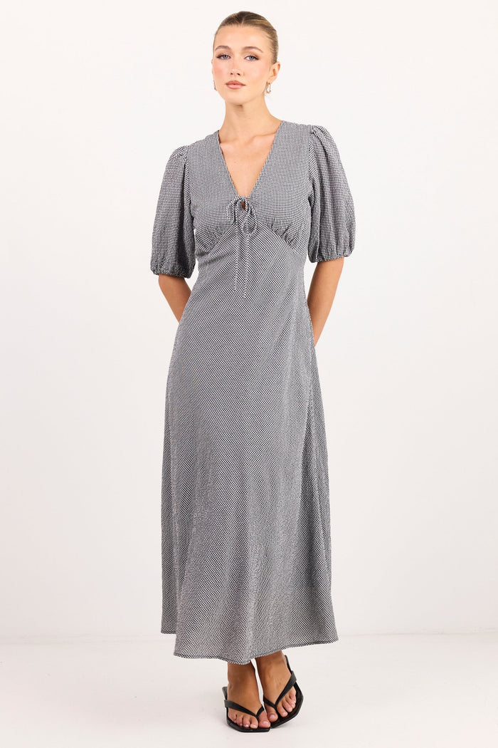 A woman modeling a gray midi-length dress with short puff sleeves, a deep V-neckline, and a gathered waist detail, paired with black sandals against a plain white studio background.