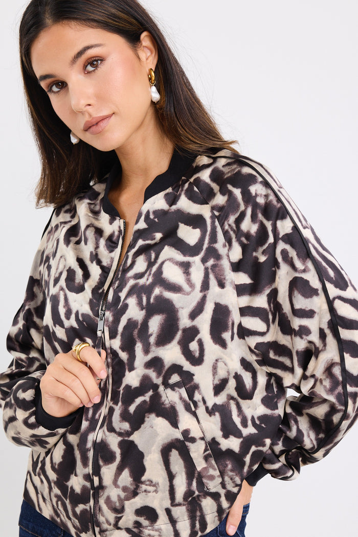 model wears a leopard bomber jacket with dark blue jeans