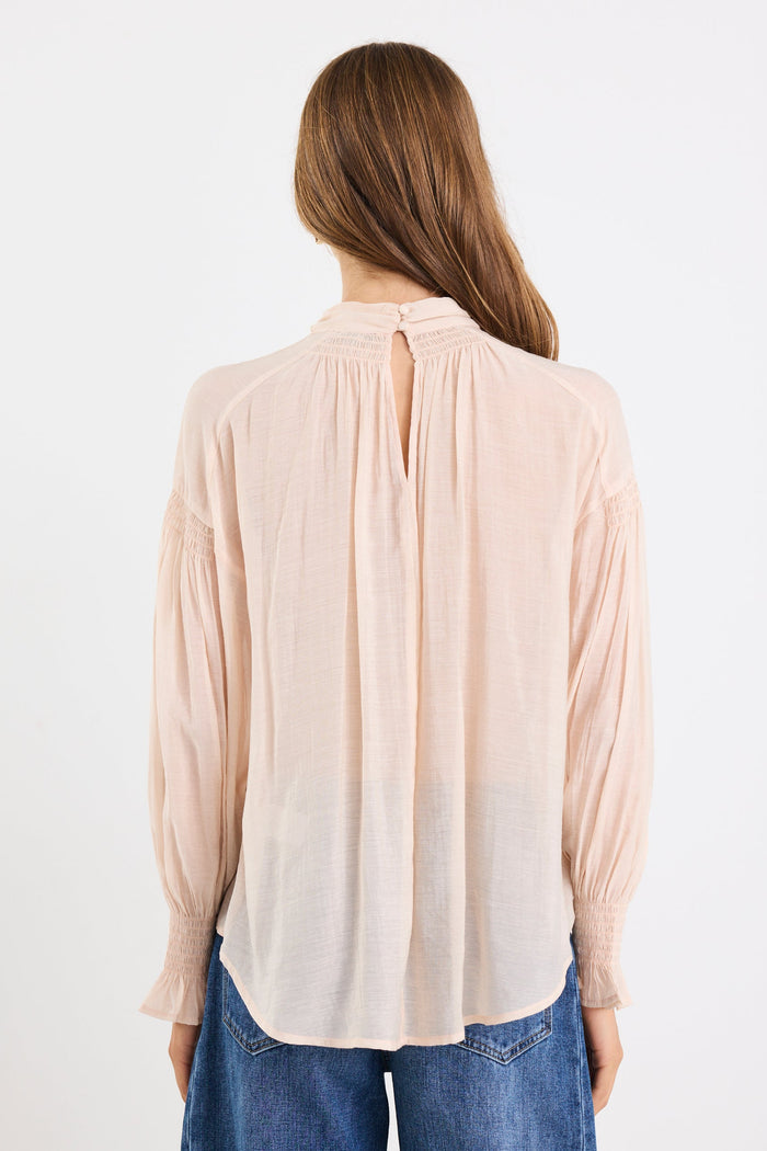 Woman wearing a beige blouse and blue jeans on a white background