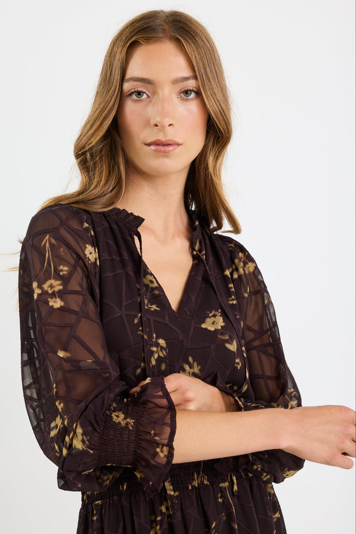 Woman wearing a dark floral lace dress against a white background