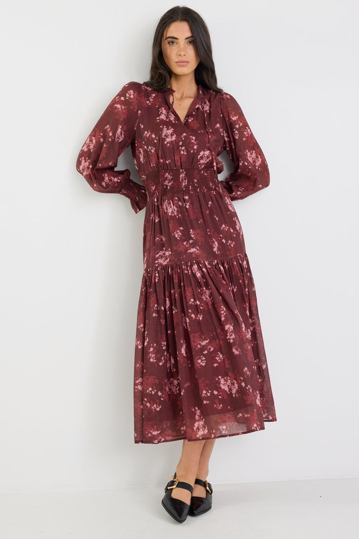 Woman wearing a burgundy floral dress against a white background