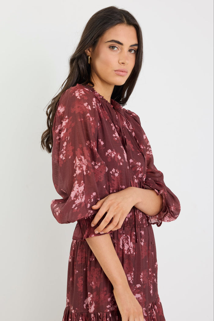 Woman wearing a burgundy floral dress against a white background
