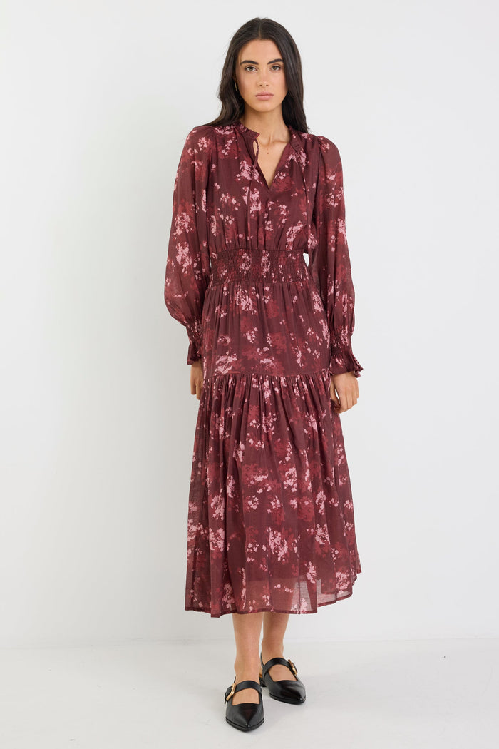 Woman wearing a burgundy floral dress on a white background