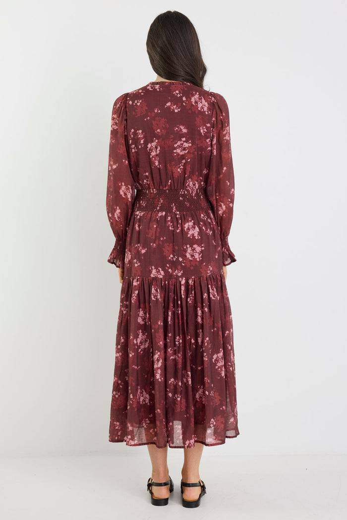 Woman wearing a burgundy floral dress on a white background