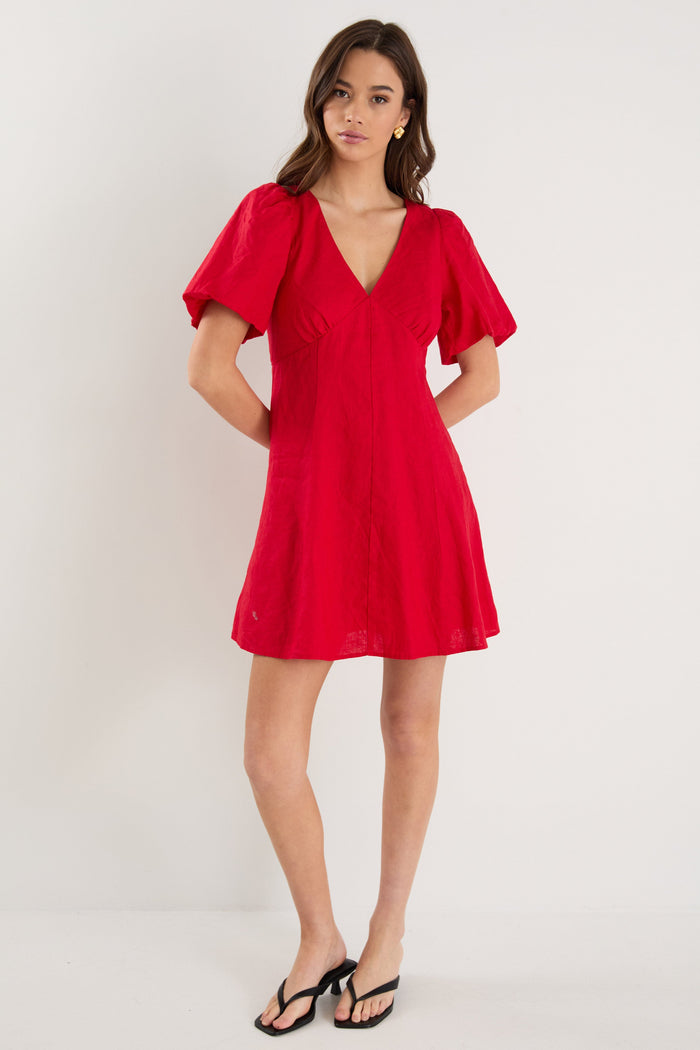 Woman wearing a red dress with ruffled sleeves against a white background