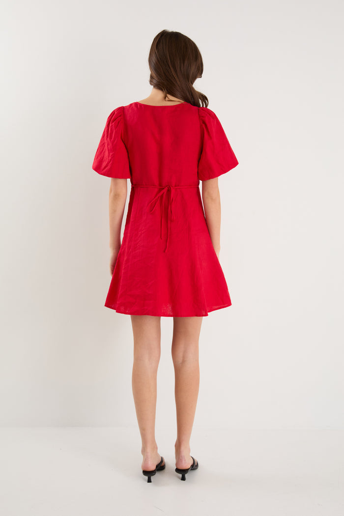Woman wearing a red dress with puff sleeves on a white background