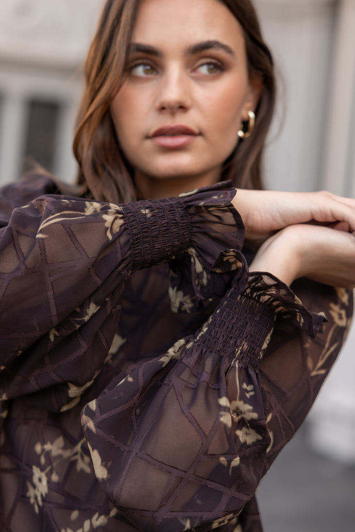 Woman wearing a dark floral blouse with a blurred background
