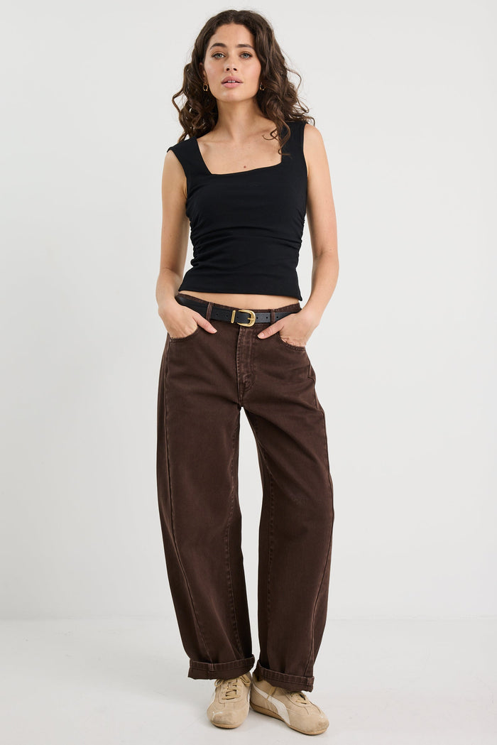 Woman wearing a black top and brown pants on a white background