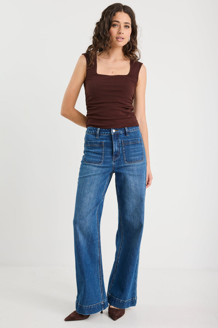 woman wearing a brown ruched top and blue jeans