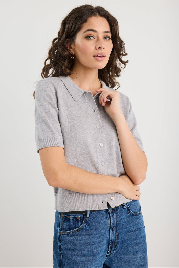 Woman wearing a grey knit and blue jeans on a white background