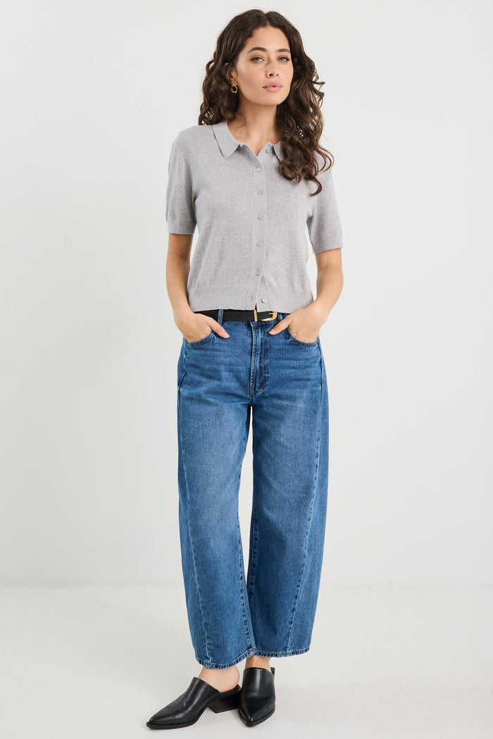 Woman wearing a grey knit and blue jeans on a white background