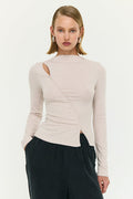 Woman wearing a beige long-sleeve top with a cutout design on a white background