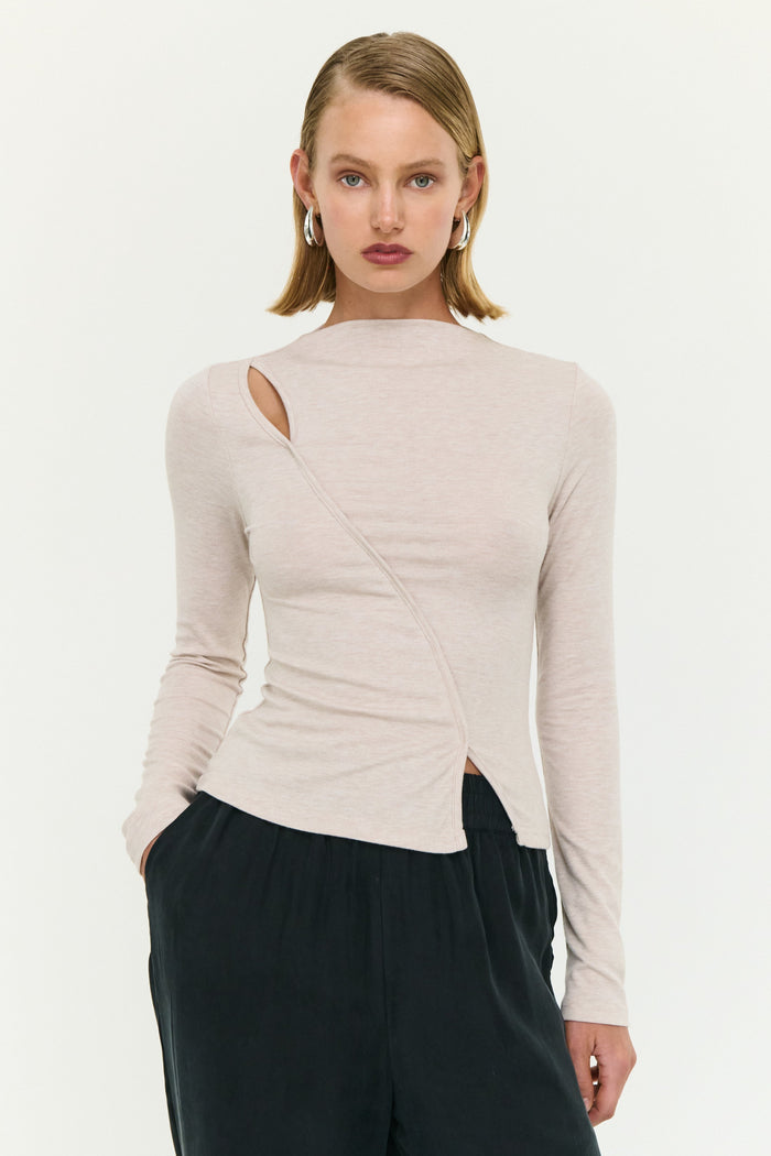Woman wearing a beige long-sleeve top with a cutout design on a white background