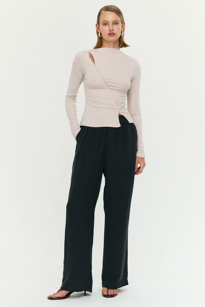 Woman wearing a beige top and black pants on a white background