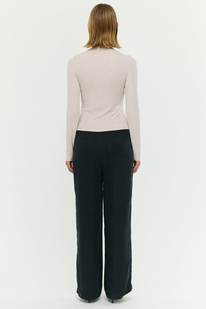 Person wearing a light-colored long-sleeve top and dark pants on a white background
