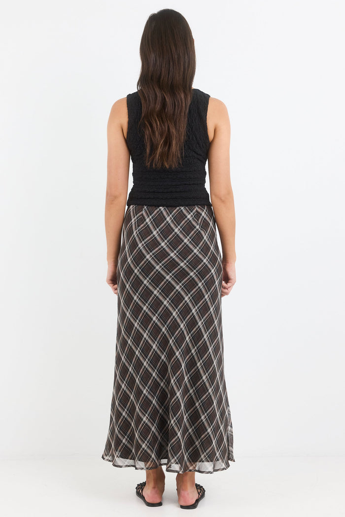 Woman wearing a black sleeveless top and patterned skirt on a white background