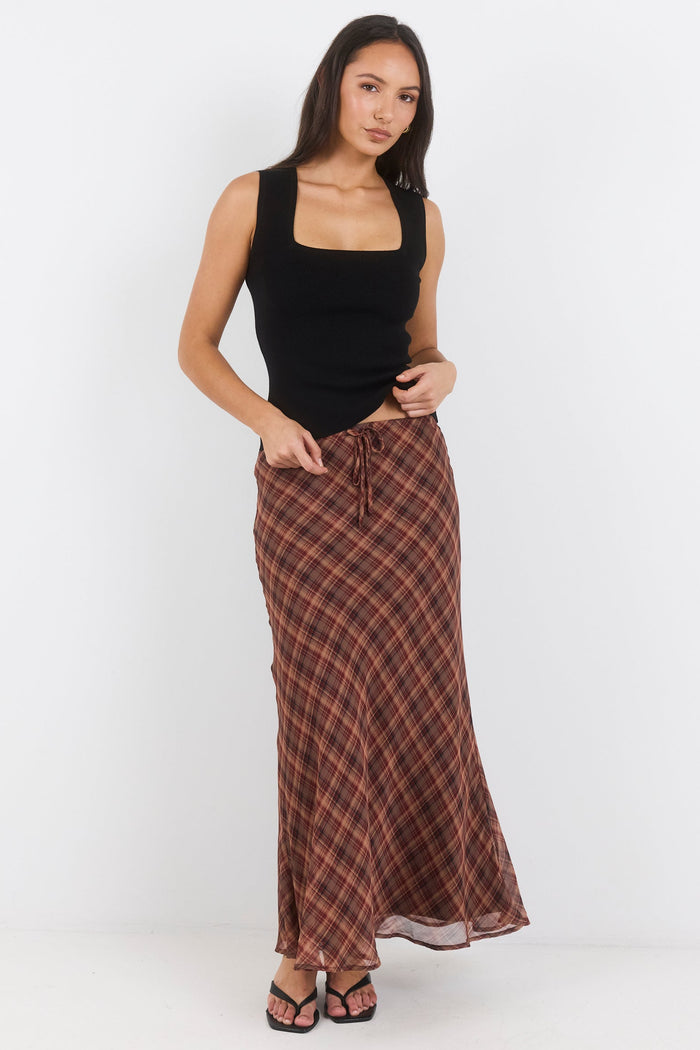 Woman wearing a black top and brown plaid skirt on a white background