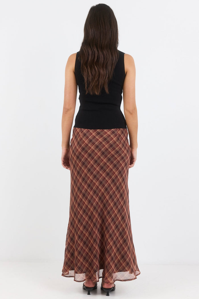 Woman wearing a black top and plaid skirt on a white background
