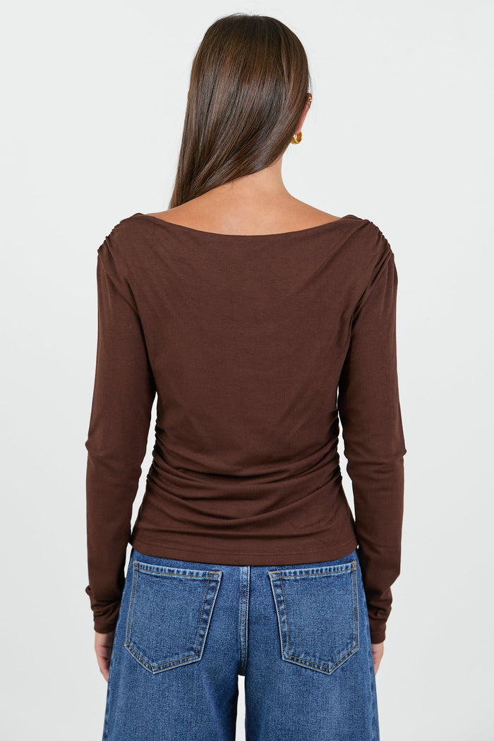Woman wearing a chocolate brown long sleeve top and blue jeans