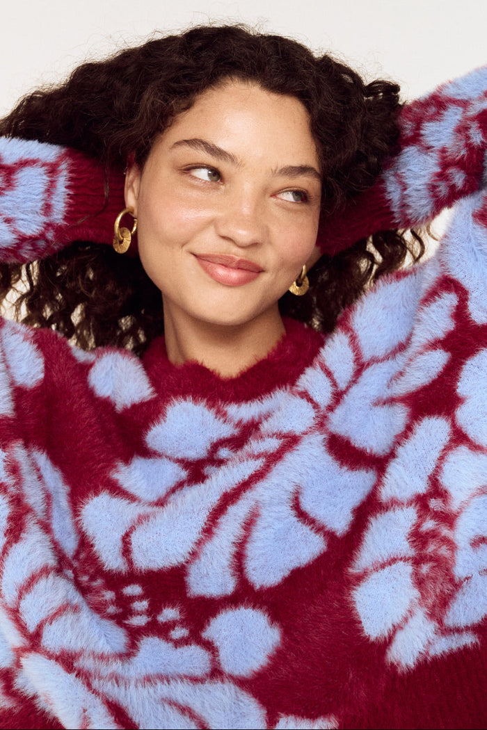 Woman wearing a red and white patterned sweater against a plain background