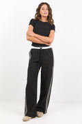Person wearing a black t-shirt and black pants with white stripes on a white background