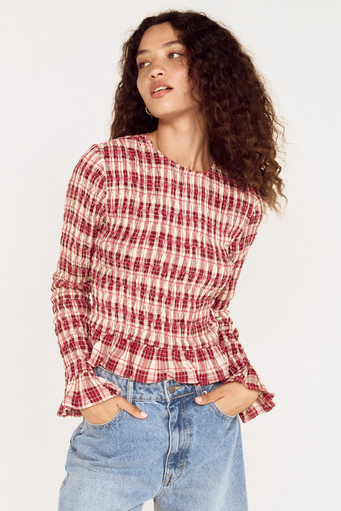 Woman wearing a red and white checkered shirt and blue jeans on a white background