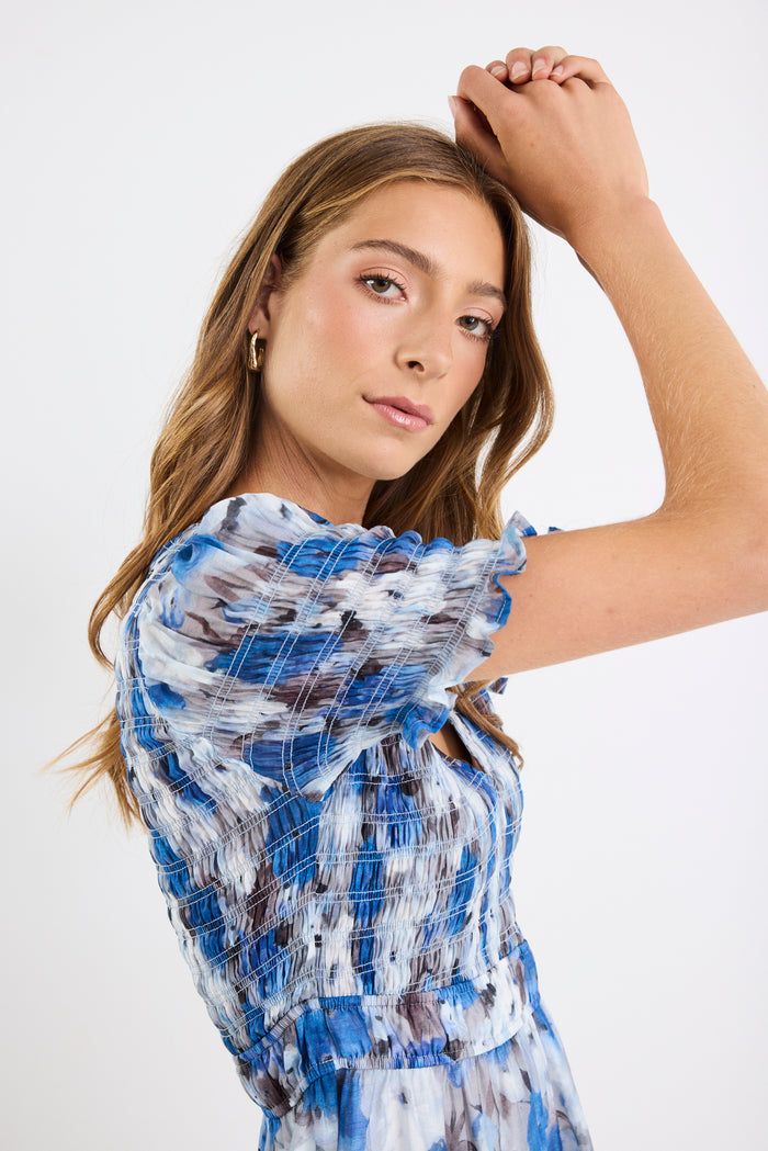 Woman wearing a blue and white patterned dress against a plain background