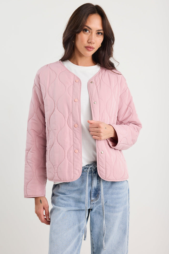 Woman wearing a pink quilted jacket and blue jeans