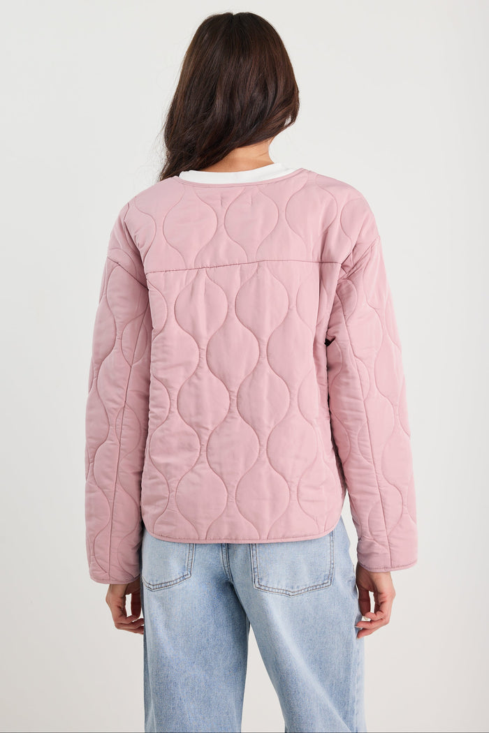 Woman wearing a pink quilted jacket and blue jeans
col_pattern