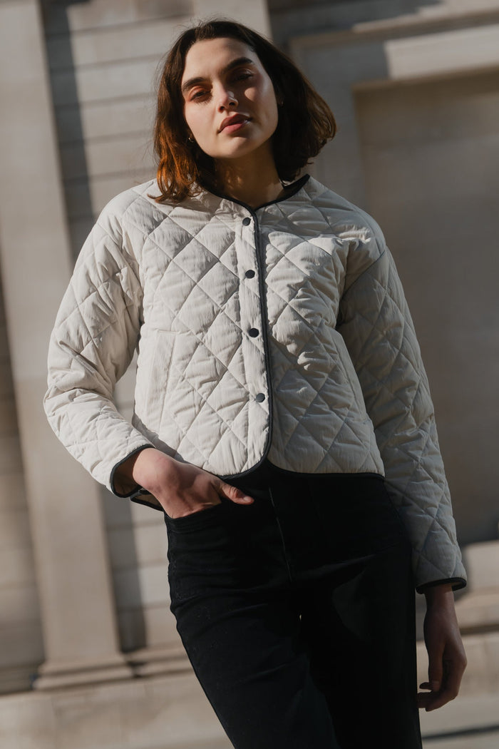 Woman wearing a quilted jacket standing in front of a classical building.