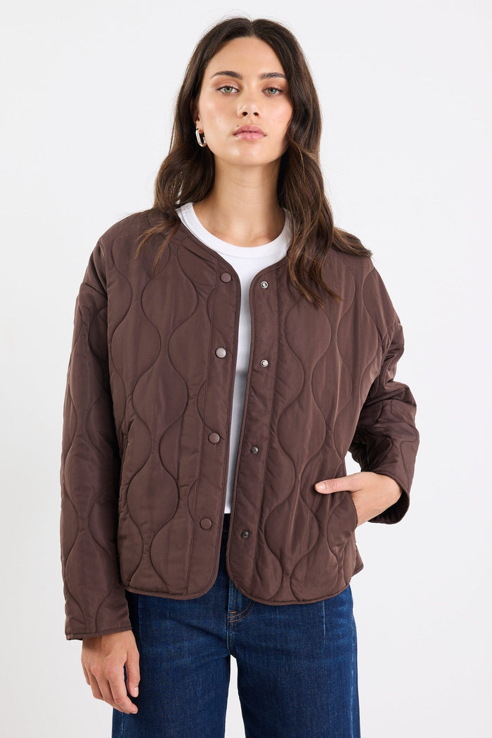 Woman wearing a brown quilted jacket on a white background