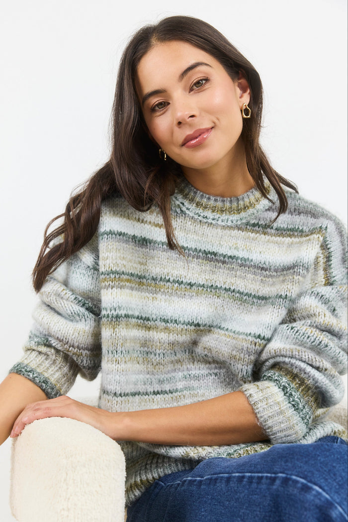 Woman wearing a striped sweater sitting on a white surface