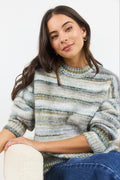 Woman wearing a striped sweater sitting on a white surface