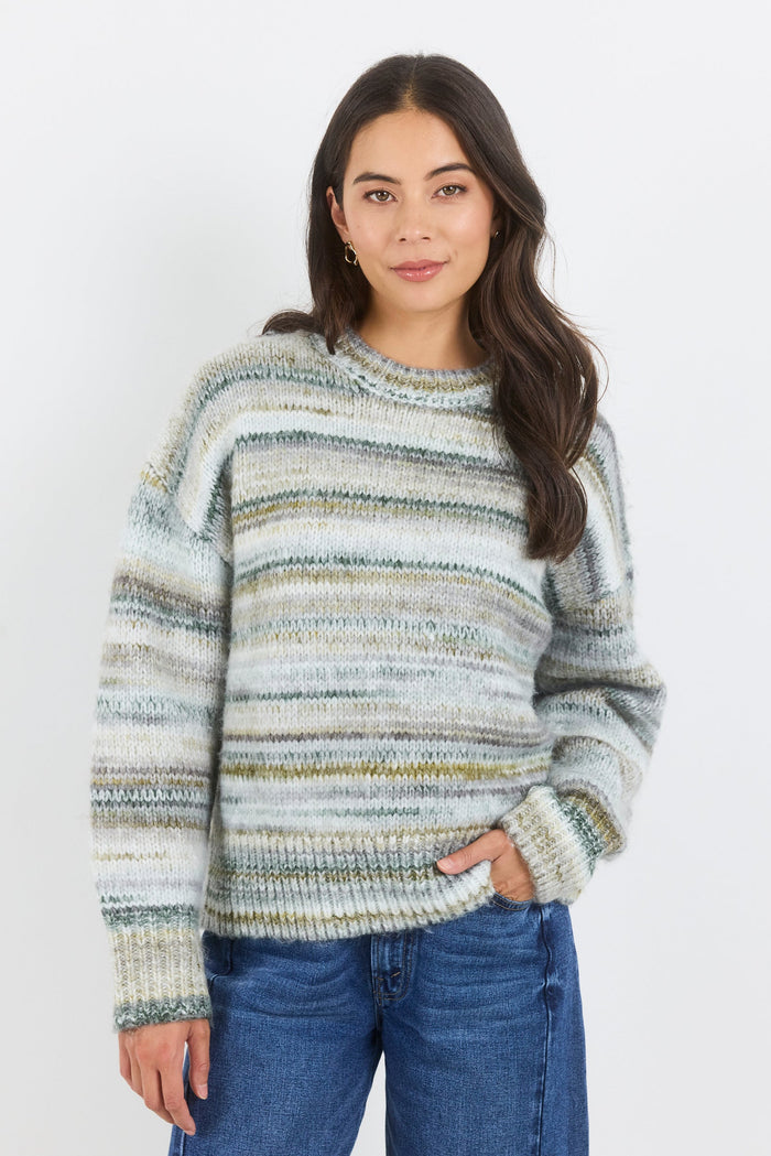 Woman wearing a striped sweater and blue jeans against a white background