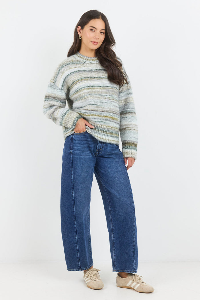 Woman wearing a striped sweater and blue jeans on a white background