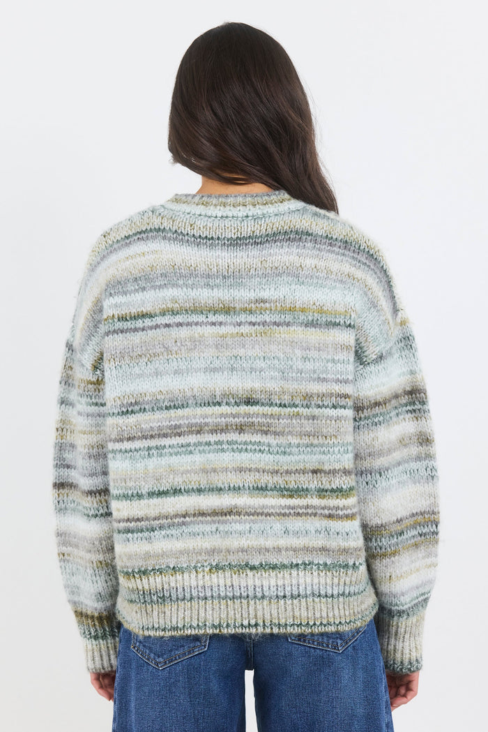 Person wearing a striped sweater and blue jeans on a white background