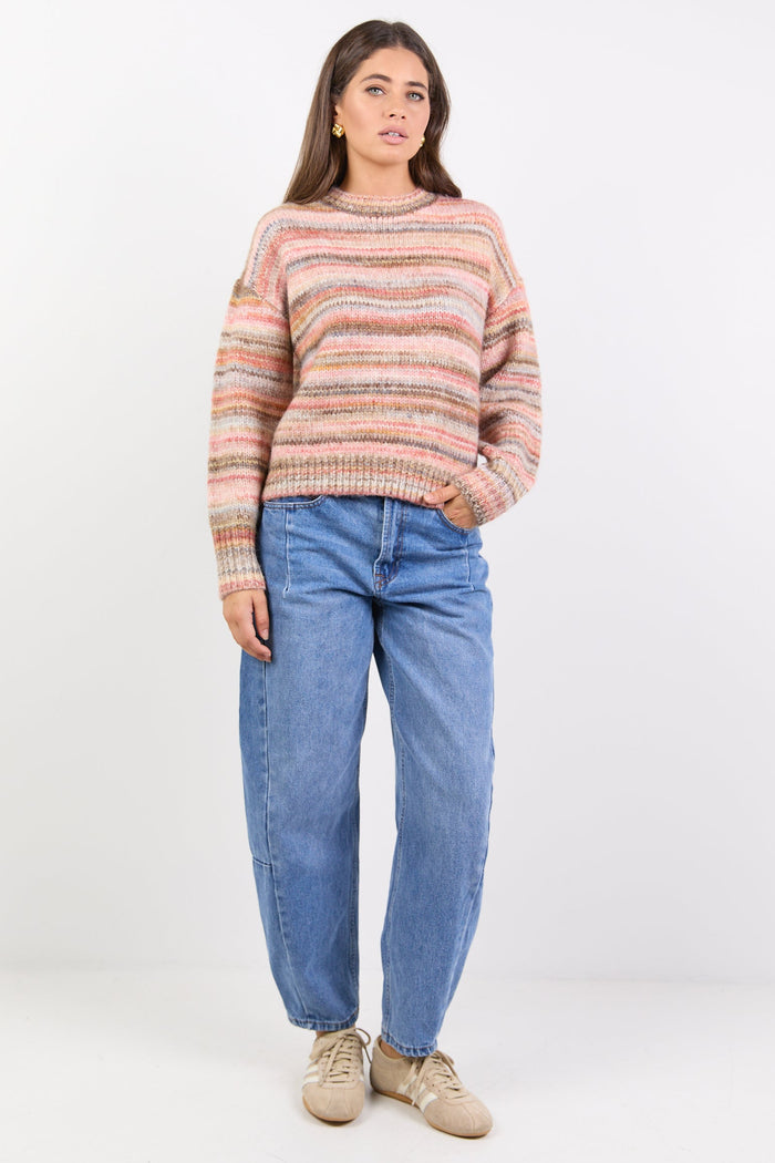 Woman wearing a striped sweater and blue jeans on a white background