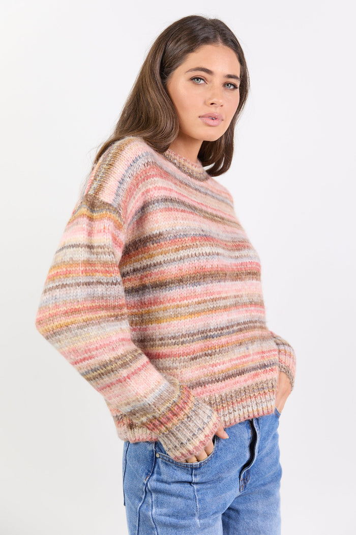 Woman wearing a multicolored sweater and blue jeans on a white background