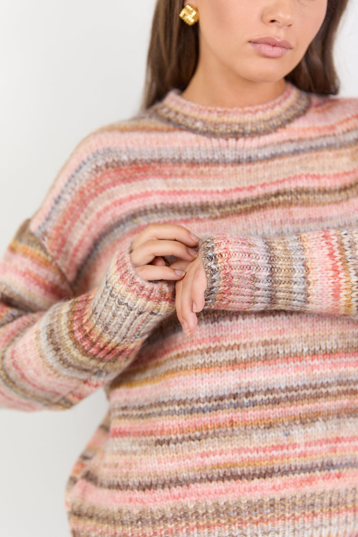 Multicolored striped sweater worn by a person on a white background