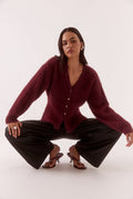 Woman wearing a burgundy cardigan and black pants on a white background
