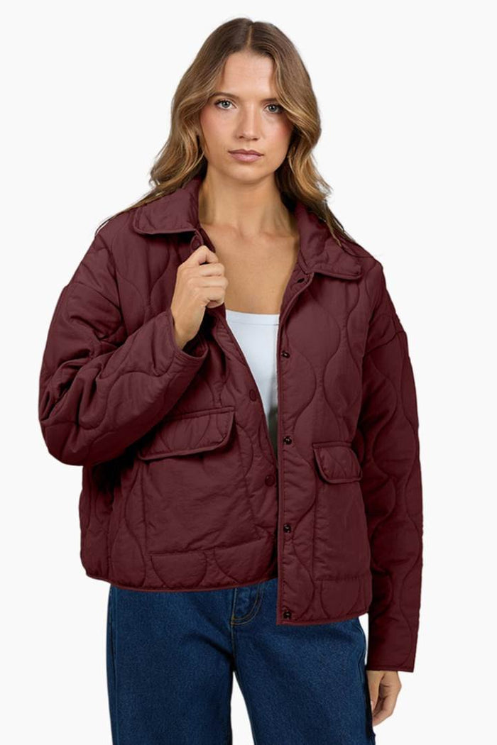 Woman wearing a maroon quilted jacket on a white background