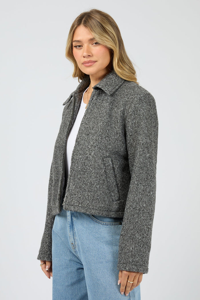 Woman wearing a gray jacket and blue jeans on a white background