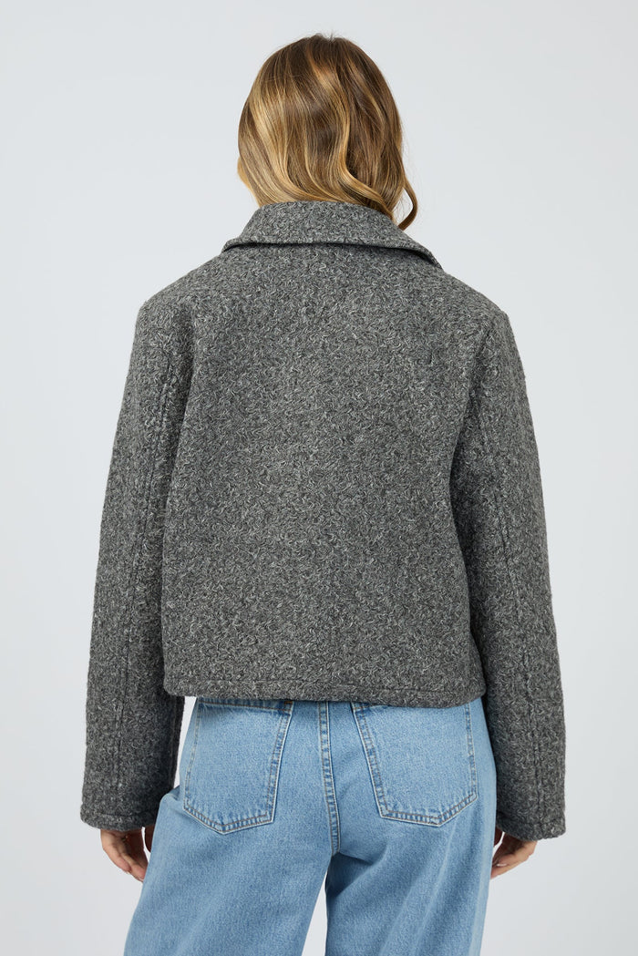 Person wearing a gray jacket and blue jeans on a white background