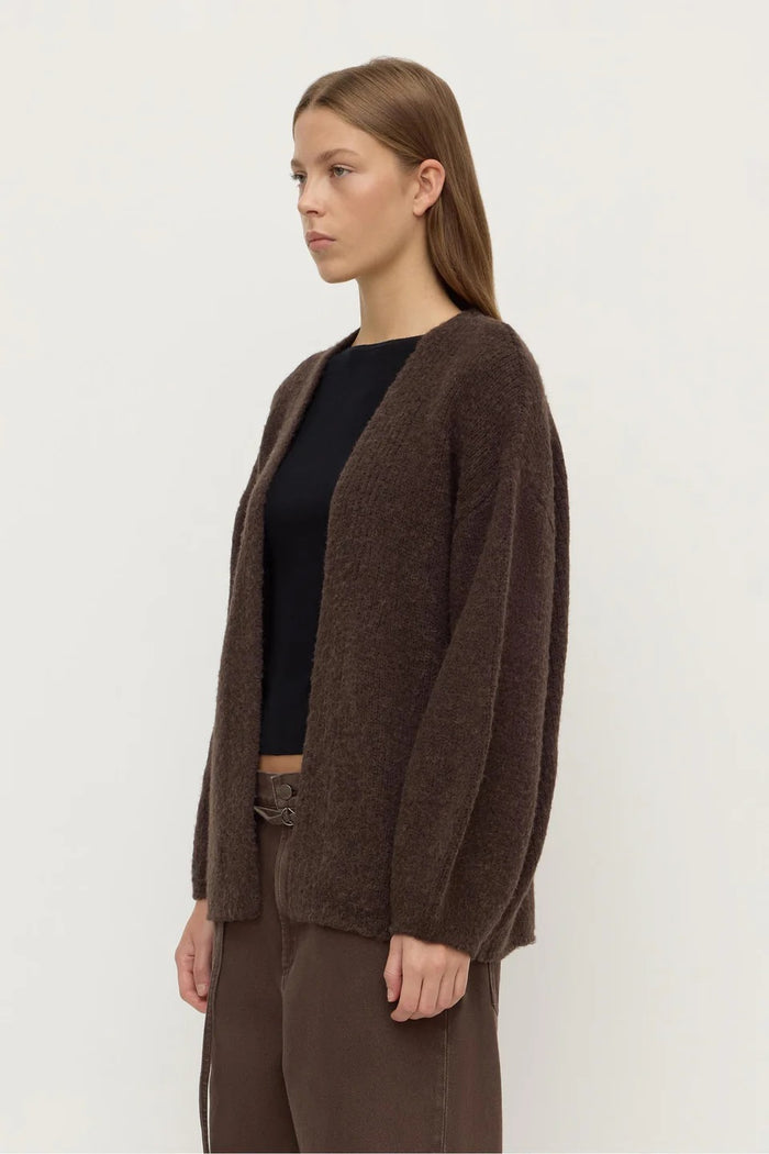 Woman wearing a brown cardigan over a black top on a white background